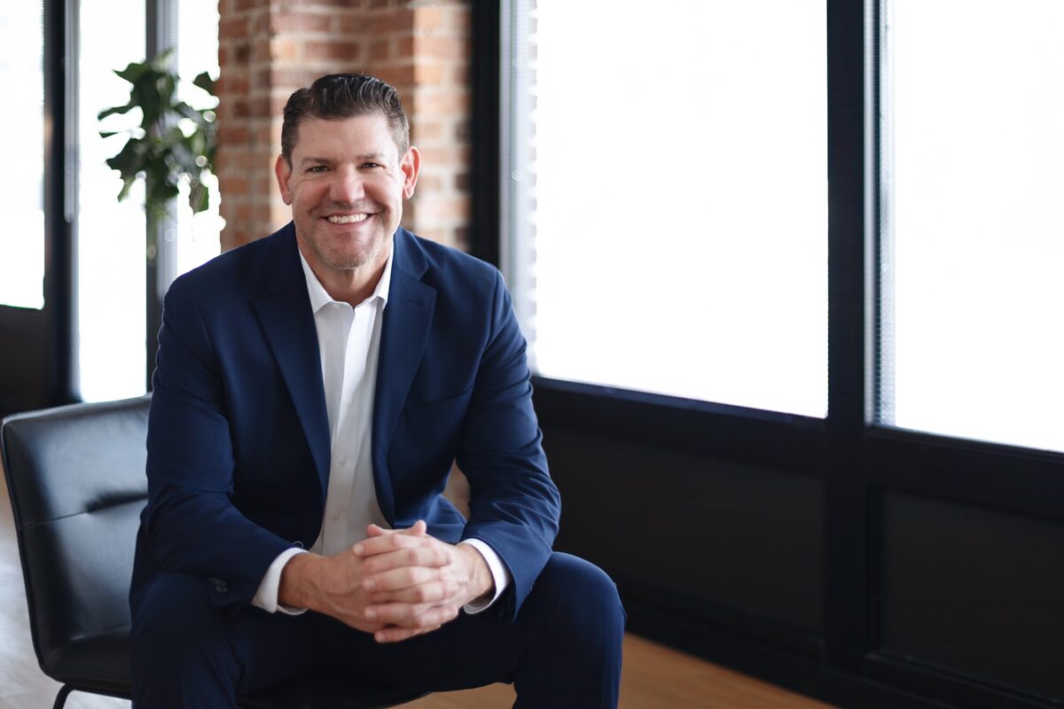 Gary Burmeister seated in a professional office wearing a navy suit.